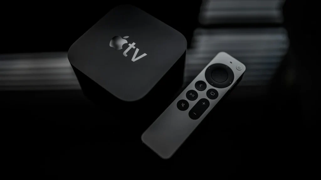 Black Apple TV box beside a silver Siri Remote on a dark glossy surface