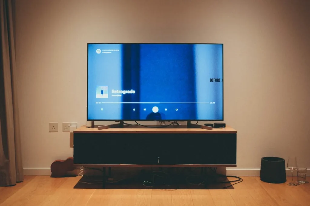 Television on a low media unit in a living room with UK plug sockets, showing a media player screen of the kind Kodi provides