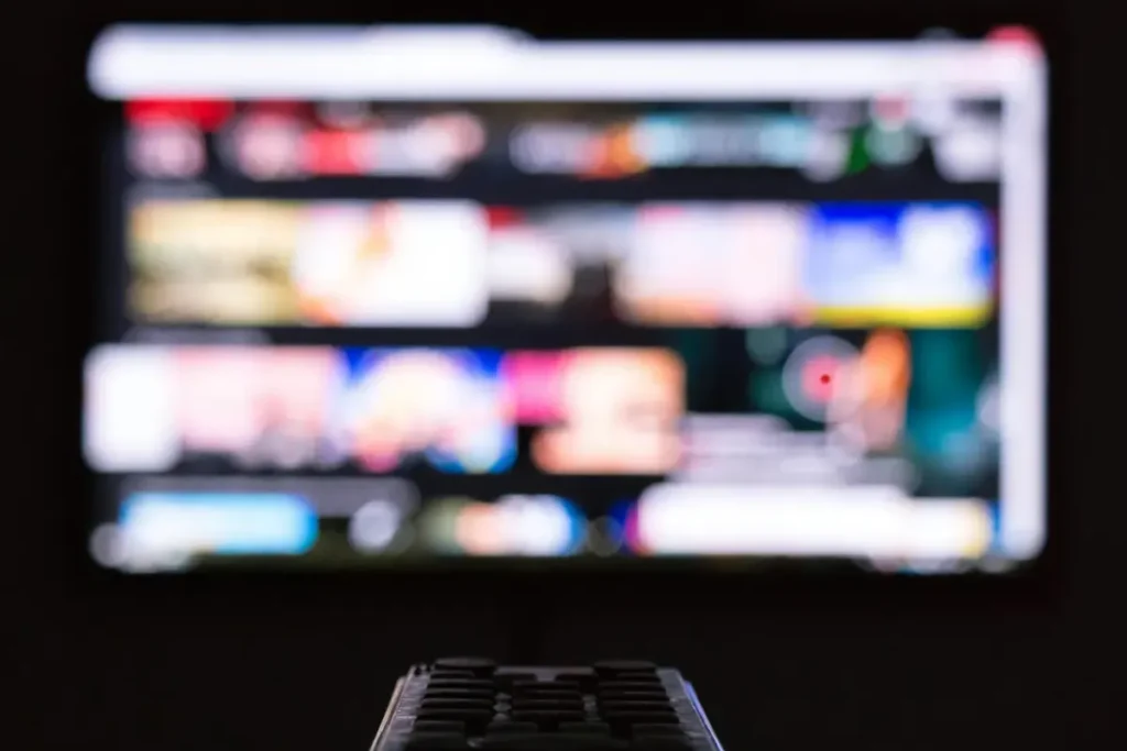Remote control pointed at an out-of-focus TV menu, illustrating IPTV player playback problems